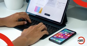 En person skriver på ett tangentbord. Intill ligger en smarttelefon.