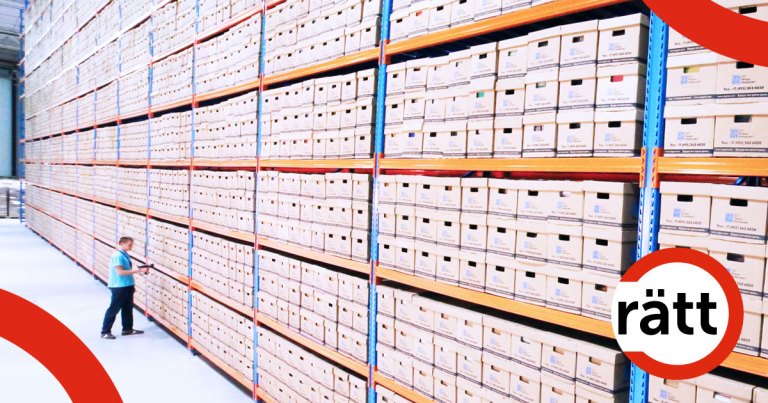 En person som ser väldigt liten ut intill en väldigt hög arkivlådehylla.