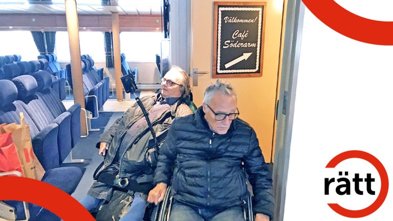 Två personer i rullstolar sitter under en Cafe-skylt som pekar uppför en trappa.