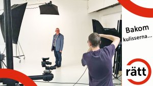 Krister iklädd blå kavaj och skjorta blir fotograferad i en ljus studio med många lampor. Fotografens rygg syns i bild.