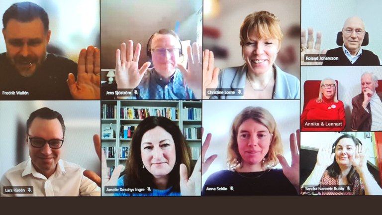 Flera personer i ett digitalt möte. Några räcker upp händerna.