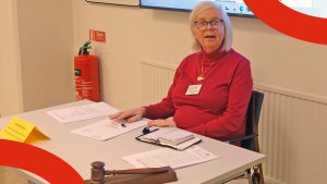 Annika Hässler i röd tröja. På bordet framför henne ligger ordförandeklubban.