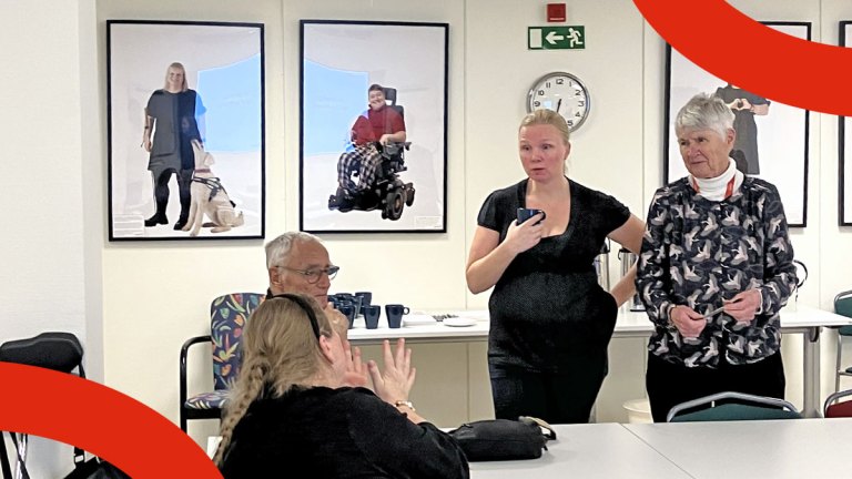 Fyra personer står och sitter tillsammans vid ett bord. De har en gruppdiskussion.