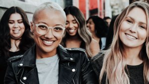 En grupp kvinnor rör sig leende genom stan.