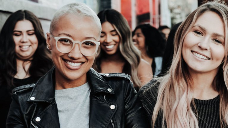 En grupp kvinnor rör sig leende genom stan.