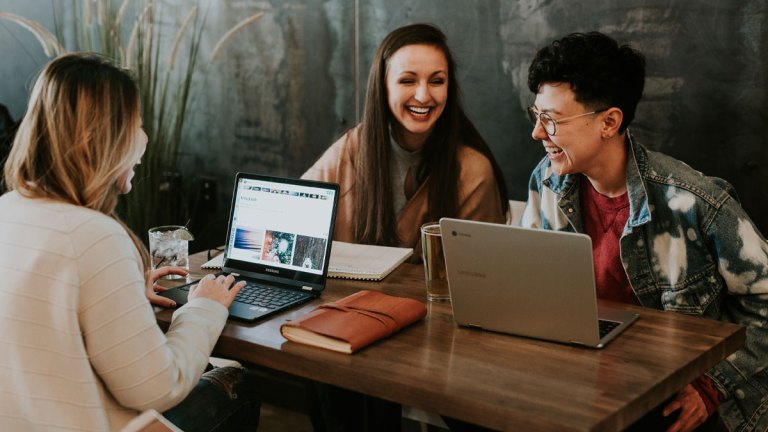 Tre personer sitter i möte med varandra och alla skrattar gott.