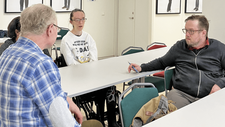 Fyra personer sitter i en grupp och diskuterar.