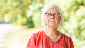 Annika Hässler ser bestämd ut. Hon har på sig en röd tröja och glasögon. I bakgrunden syns träd och växtlighet.
