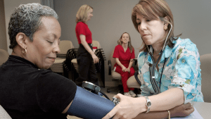 En sjuksköterska mäter blodtrycket på en patient.