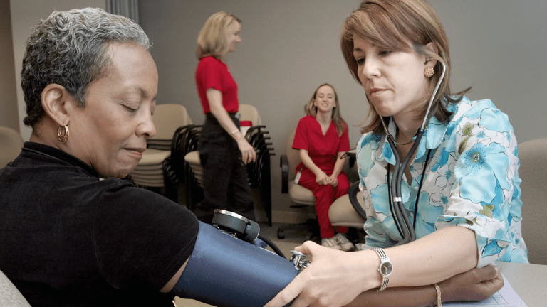 En sjuksköterska mäter blodtrycket på en patient.
