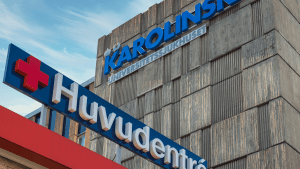 En gråbetongfasad, med skyltar som upplyser om att detta är Karolinska universitetssjukhusets huvudentré.