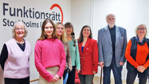 Presidiet och mp-politiker står framför Funktionsrätt Stockholms läns logga