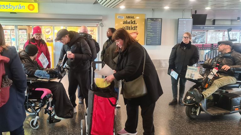 Flera personer har samlats i Stationshuset i Älvsjö. De ser ut att förbereda sig inför en samling.