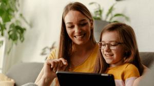 En kvinna och ett barn använder en surfplatta. Båda ler glatt. Bilden är samma som på rapporten om digitalt utanförskap.