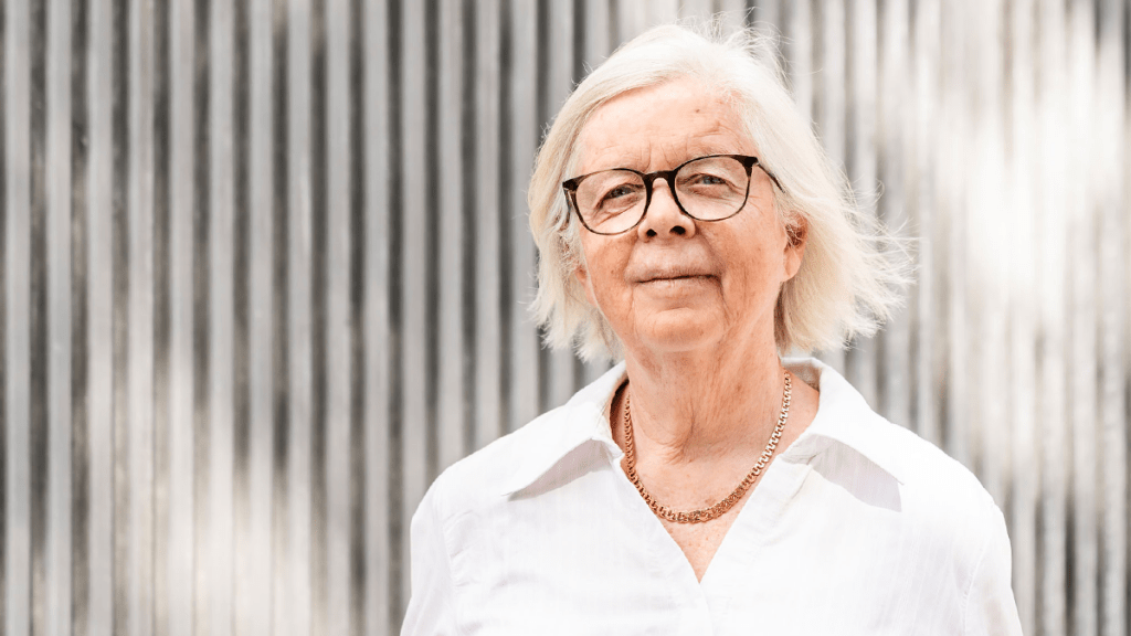 Porträttbild på Annika Hässler, en äldre kvinna med glasögon och vit skjorta.