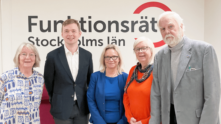 Fem personer står på rad framför vår logga. Alla ler in i kameran.