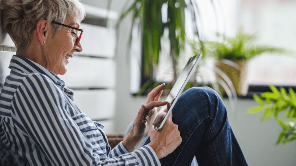 Närbild på en äldre kvinna som ler och tittar på en telefon