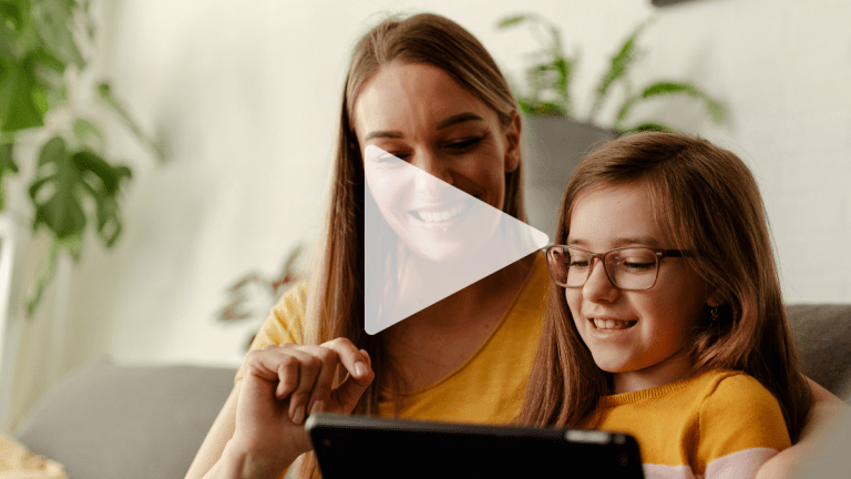 En kvinna och ett barn använder en surfplatta. Båda ler glatt. Ovanpå bilden ligger en pil, en spela-knapp, som på ett filmklipp.