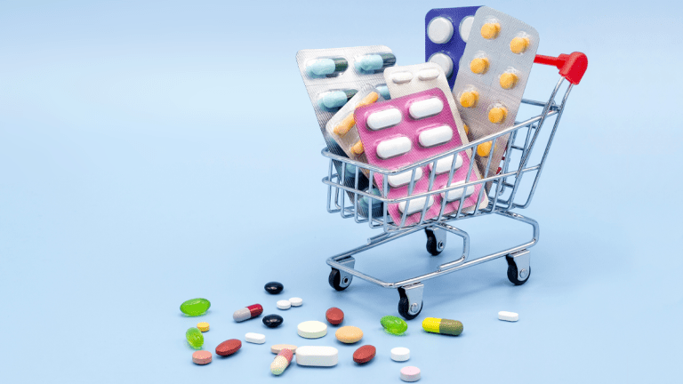 En kundvagn i miniatyr, fylld med flera olika förpackningar med piller och tabletter.