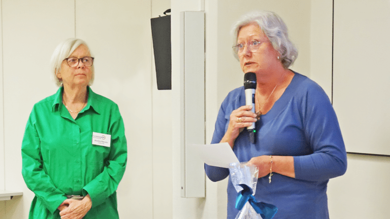 Annika tittar på Åse, som talar i mikrofon.