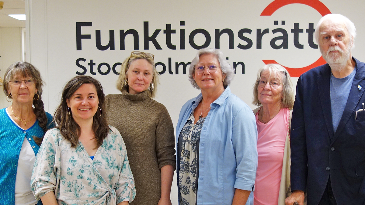 Sex personer står på rad framför en vägg med vår logga på. De ler in i kameran.