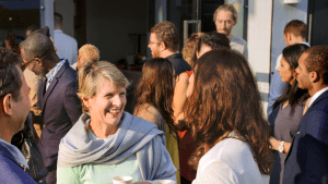 En stor grupp människor står i mindre grupper och samtalar. De ser glada ut.