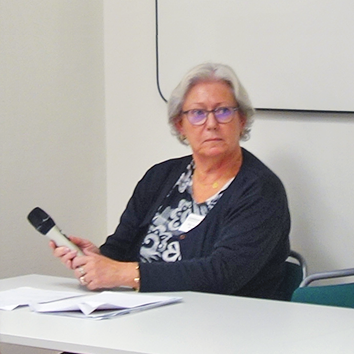 Åse Johansson-Kristiansen sitter vid ett bord och håller en mikrofon i händerna.