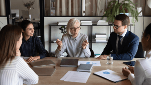 Flera personer sitter runt ett bord och diskuterar.
