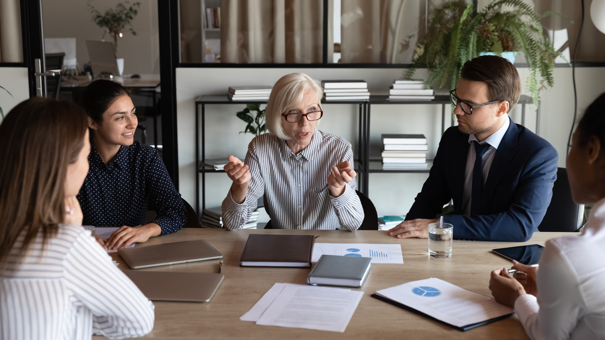 Flera personer sitter runt ett bord och diskuterar.