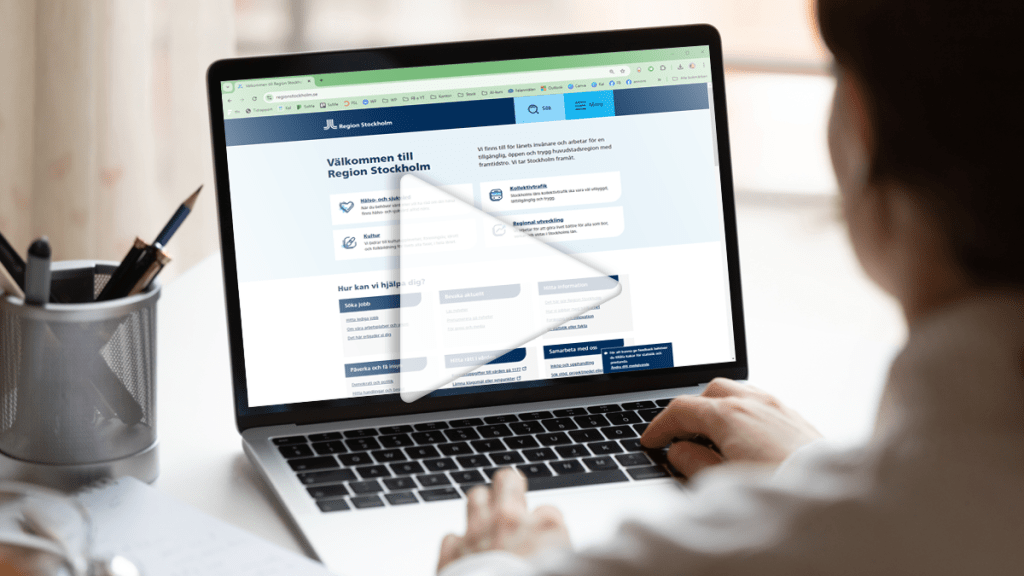 En person syns snett bakifrån. Personens händer är på tangentbordet på en laptop. På skärmen syns Region Stockholms hemsida. På bilden ligger en pil, som en startknapp för ett filmklipp.