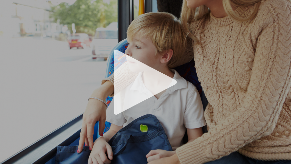 En spela-knapp ligger ovanpå en bild och ger en ledtråd om att det rör sig om en film. På bilden sitter en pojke med en ryggsäck i knät ombord på en buss och tittar ut genom fönstret. Hans mamma sitter på platsen bredvid honom och håller ena armen om hans axlar.