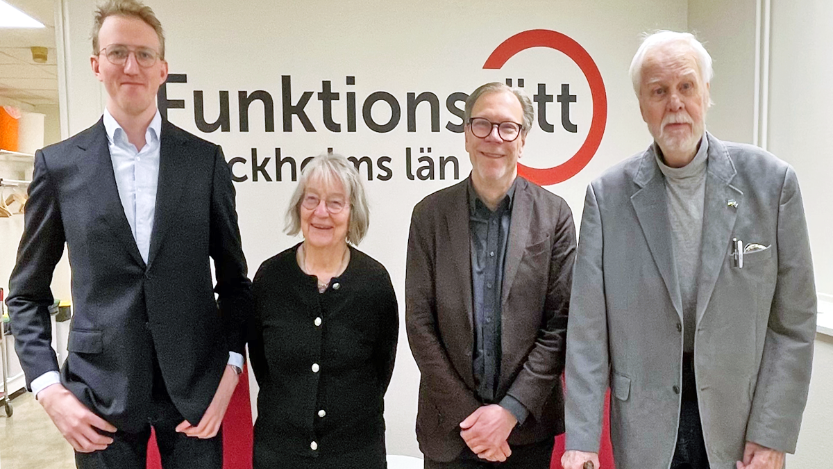 Fyra personer står på rad framför Funktionsrätt Stockholms läns logga. Alla ler mot kameran.