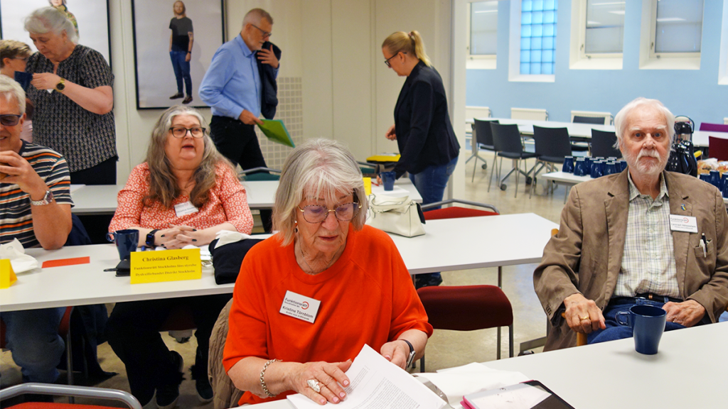Nästan alla sittplatser närmast fikabordet är fyllda med besökare. Gästerna passar på att få i sig lite fika innan mötet startar.