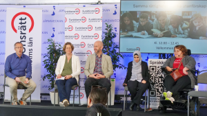 Barntema på Järvaveckan: fem personer sitter på rad på en scen. Personen längst till höger sitter i rullstol. Längst till vänster sitter moderatorn och pratar.