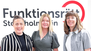 Vad gör Patientnämnden: Gabrielle, Pia och Ida står framför vår logga. Alla ler. Gabrielle har uppsatt, mörkt hår och bär en svartvit-randig jacka. Pia har utsläppt, blont hår och bär en grågrön klänning. Ida har axellångt brunt hår och bär en smårutig skjorta och glasögon.