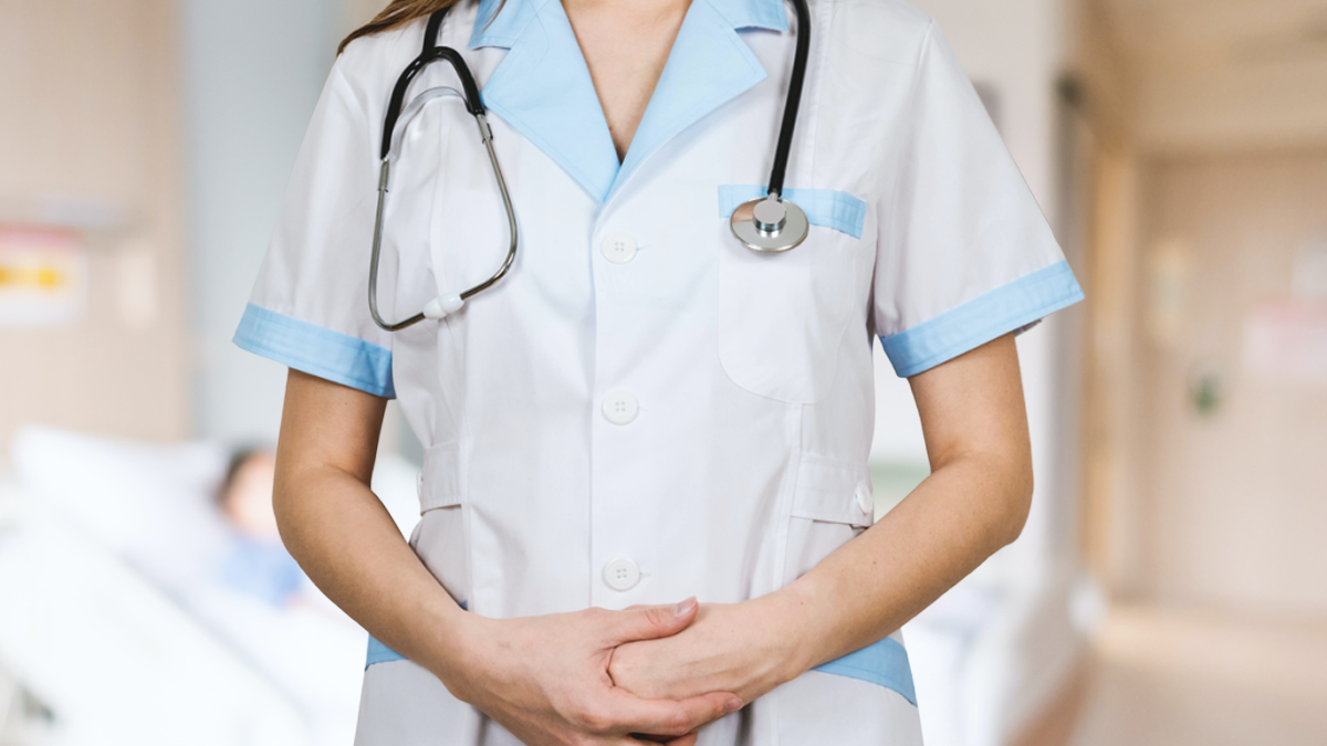 En person i vita sjukhuskläder och ett stetoskop om halsen.
