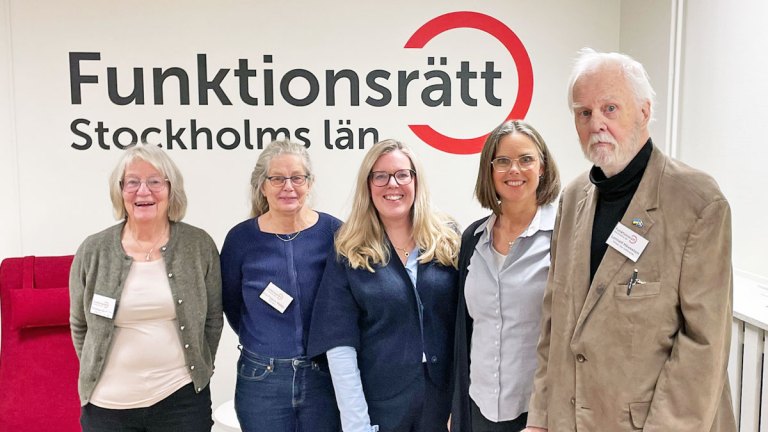 Helena och Britta från Regionen står framför Funktionsrätt Stockholms läns logga tillsammans med Kristina, Eva och Lennart från vår styrelse. De ler glatt.