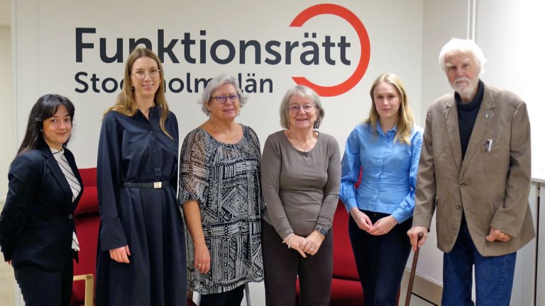 Vårt presidium och tre representanter från Centerpartiet står framför en vägg med Funktionsrätt Stockholms läns logga.
