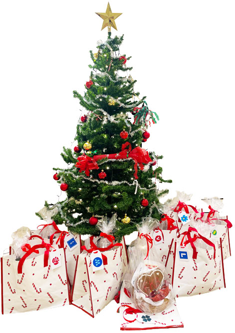 Under en smyckad julgran står 8 kassar med stora, röda rosetter och en etikett med vardera av Region Stockholms politiska partier på.