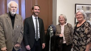 Vårt presidium och en representant från Moderaterna står på rad. En av dem håller en Halloween-dekoration i form av en dödskalle.