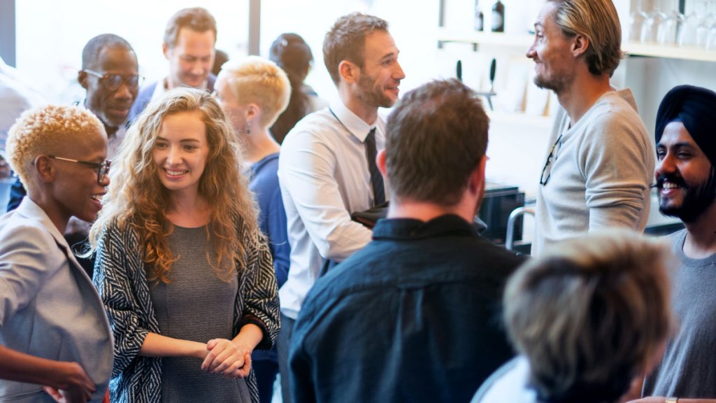 En grupp personer som minglar. De ler och pratar med varandra.