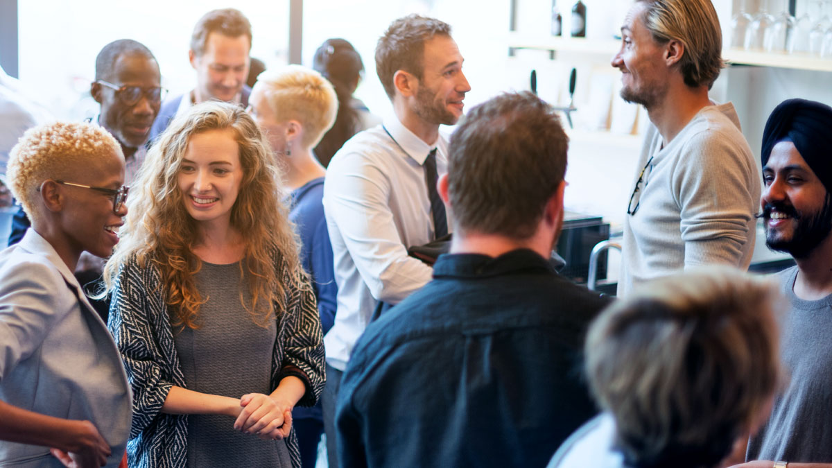 En grupp personer som minglar. De ler och pratar med varandra.