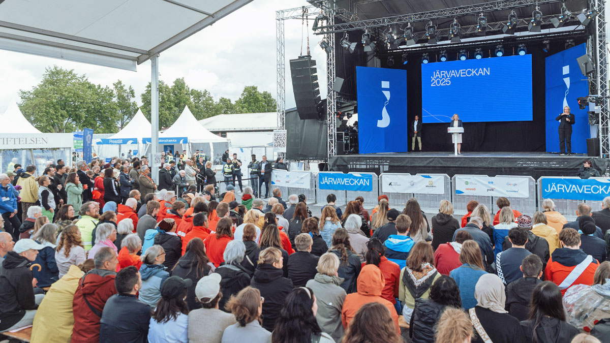 En politiker står på Järvaveckans stora scen, framför en stor folksamling. Vi vill göra gemensam sak på Järvaveckan!