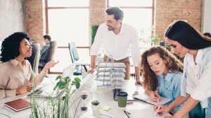 Två spontanmöten i ett luftigt kontorslandskap. En kvinna och en man pratar leendes. Två kvinnor mittemot fokuserar på ett dokument.