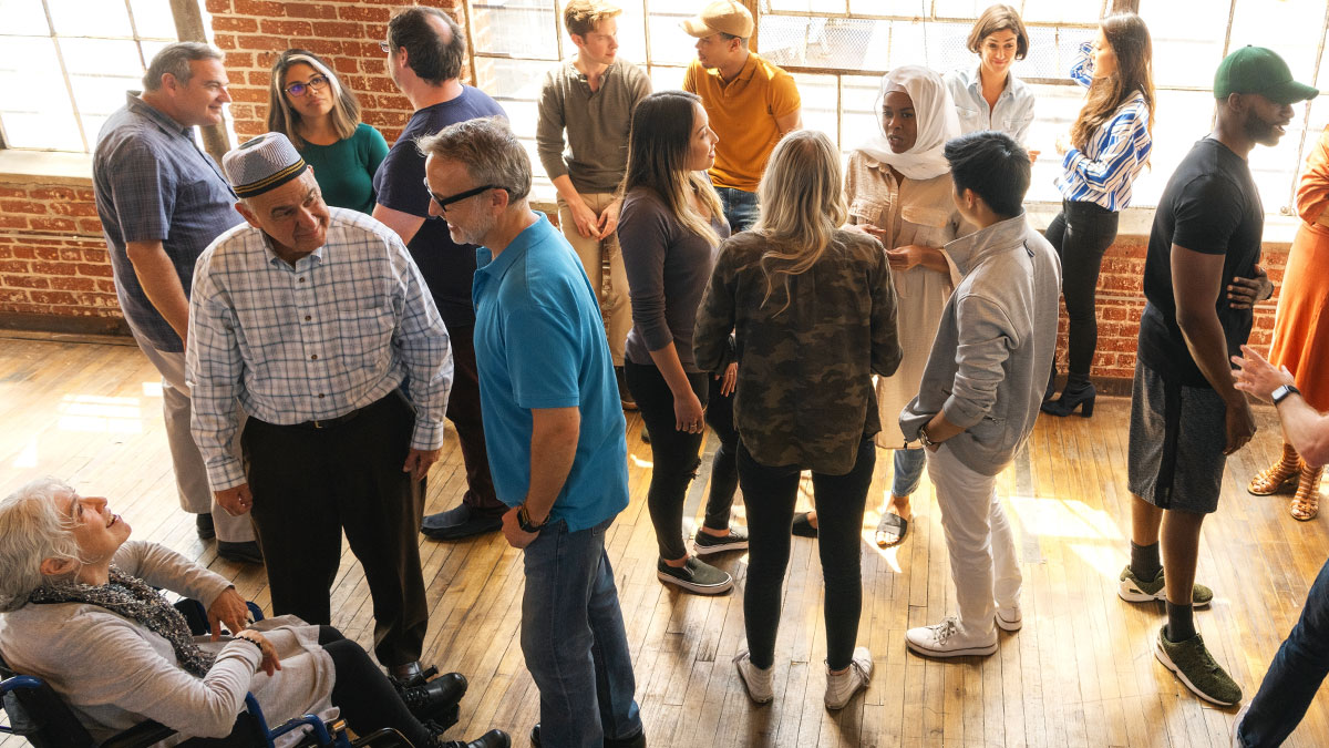 En grupp personer i olika åldrar befinner sig i små klungor och pratar med varandra. De ser ut som riktiga mingelproffs!