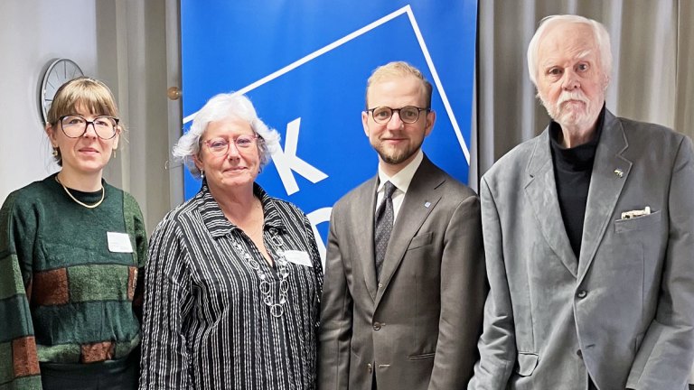 Fyra personer står på rad och ler mot kameran.