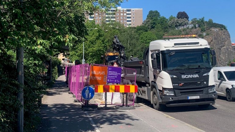 En bit av en gata är avspärrad med staket. En orange skylt med texten hållplatsen flyttad.