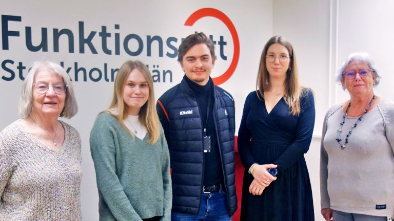 Vårt presidium och tre representanter från C står framför en vägg med Funktionsrätt Stockholms läns logga.