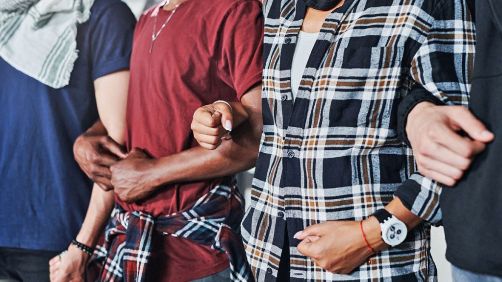 Flera personer står intill varandra med ihoplänkade armar.