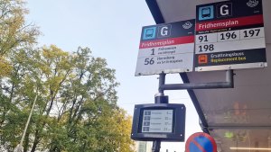 Två analoga skyltar vid en busshållplats informerar om vilka linjer som stannar där. En digital skylt under dem listar fyra bussar med beräknad ankomsttid.